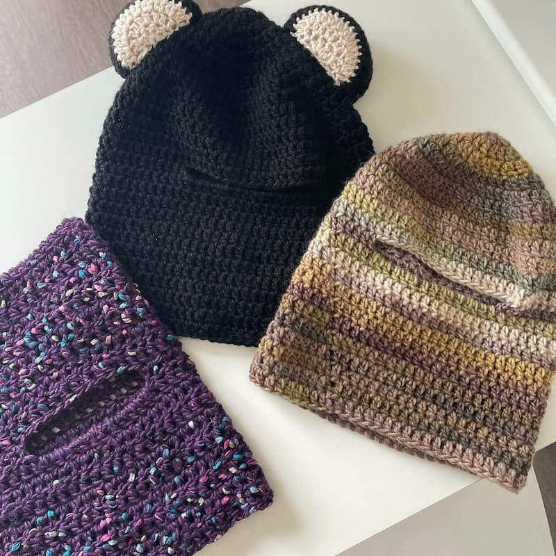 Cagoules au crochet faites main, de trois couleurs différentes, violette, noire et beige et un mélange de vert.